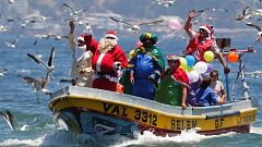 Un hombre vestido con un traje de Papa Noel saluda a la gente desde el bote