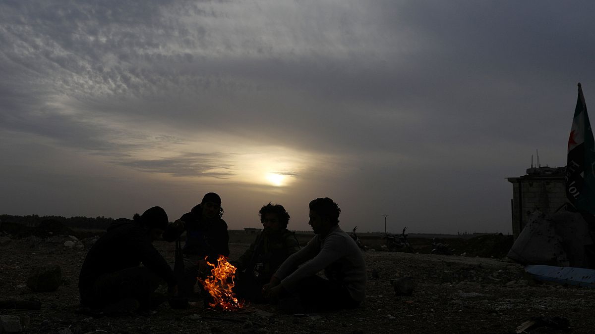 Rebeldes sírios sentados junto a uma fogueira na região de Dael