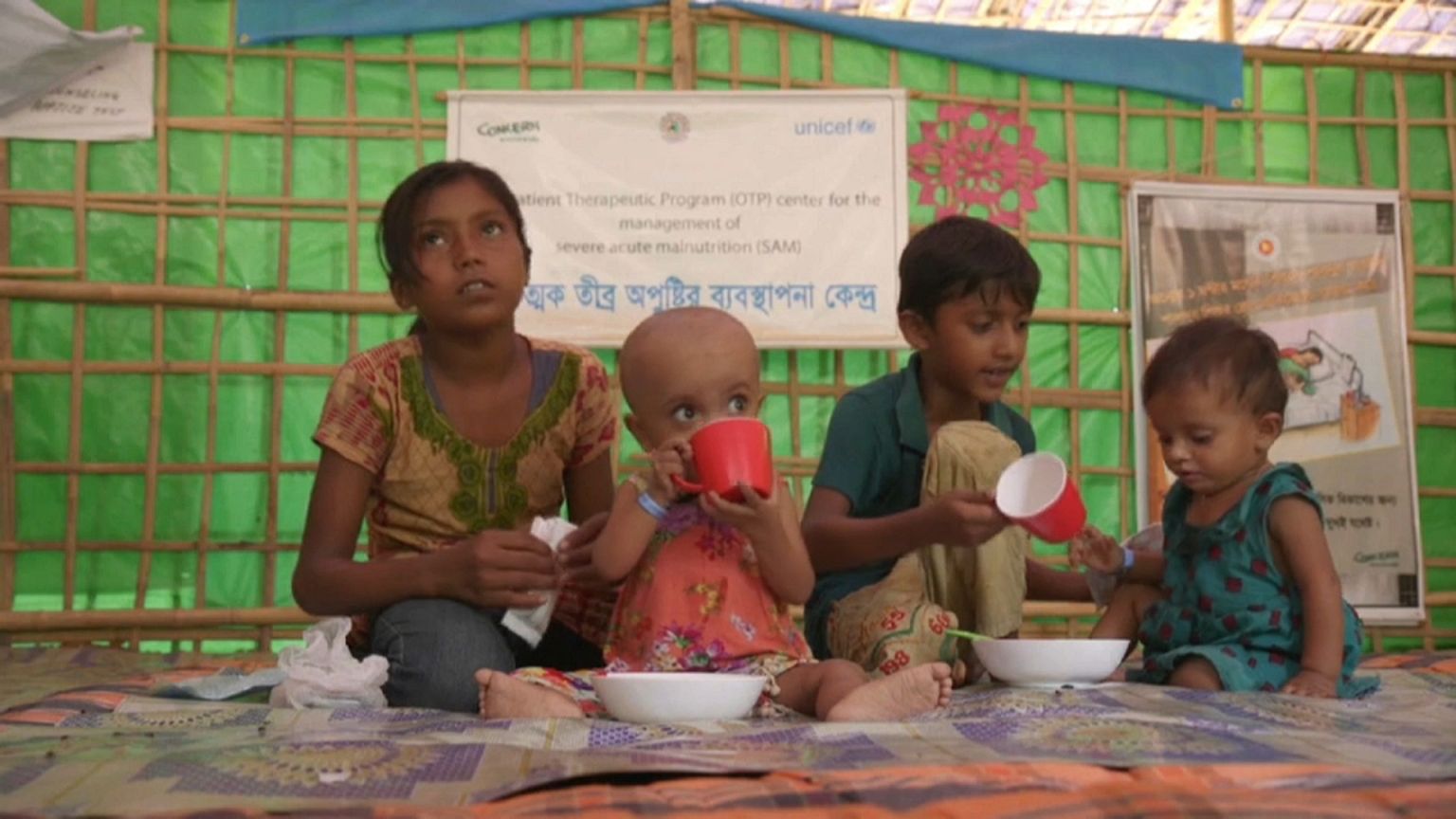 Vier Kinder sitzen in einem Unicef-Zelt auf dem Boden.