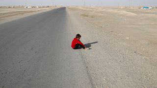 طفل شردته الحرب يجلس على قارعة الطريقة بقرية كرامة شرق الرقة