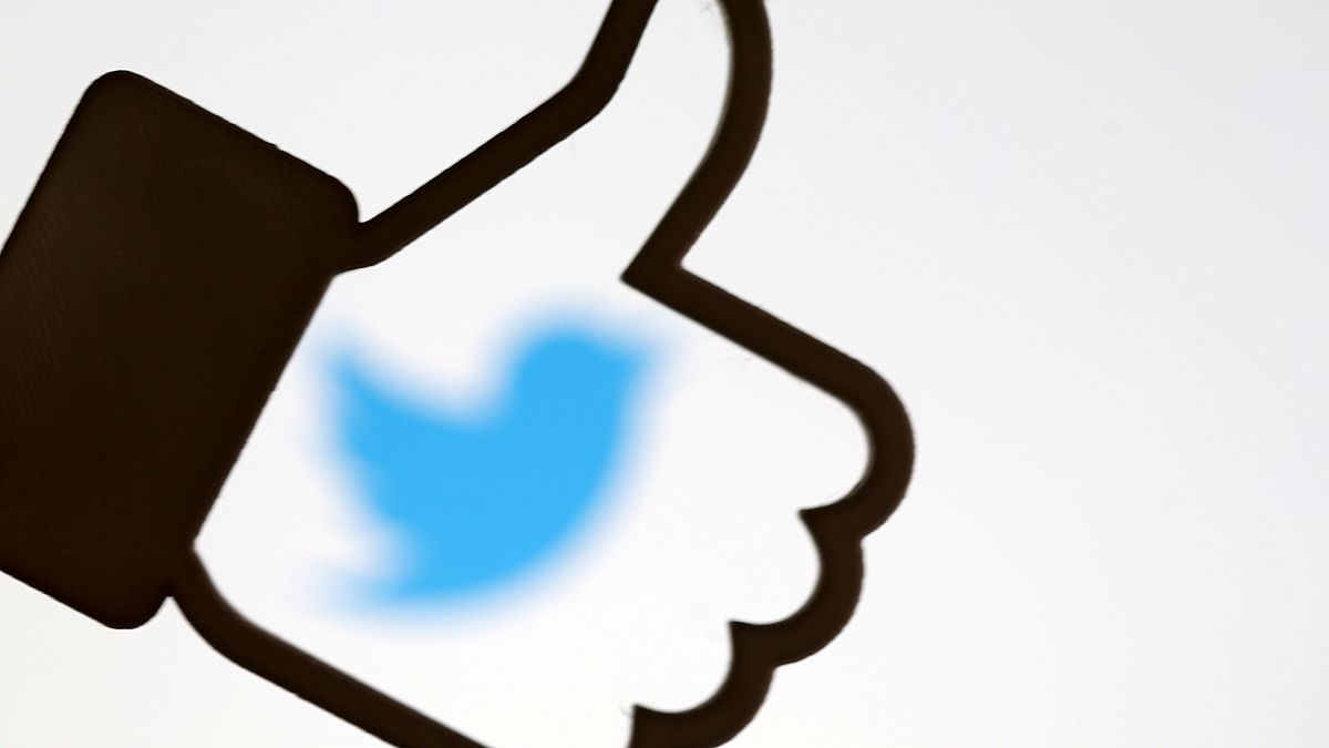 A 3D-printed Facebook like button is displayed in front of the Twitter logo