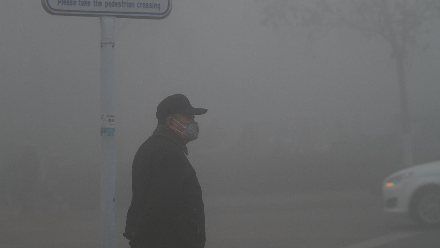 A man wearing a mask stands amid heavy fog in Jinan, Shandong province