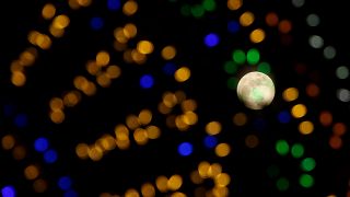 The 'supermoon' full moon is seen through Christmas lights in Valletta