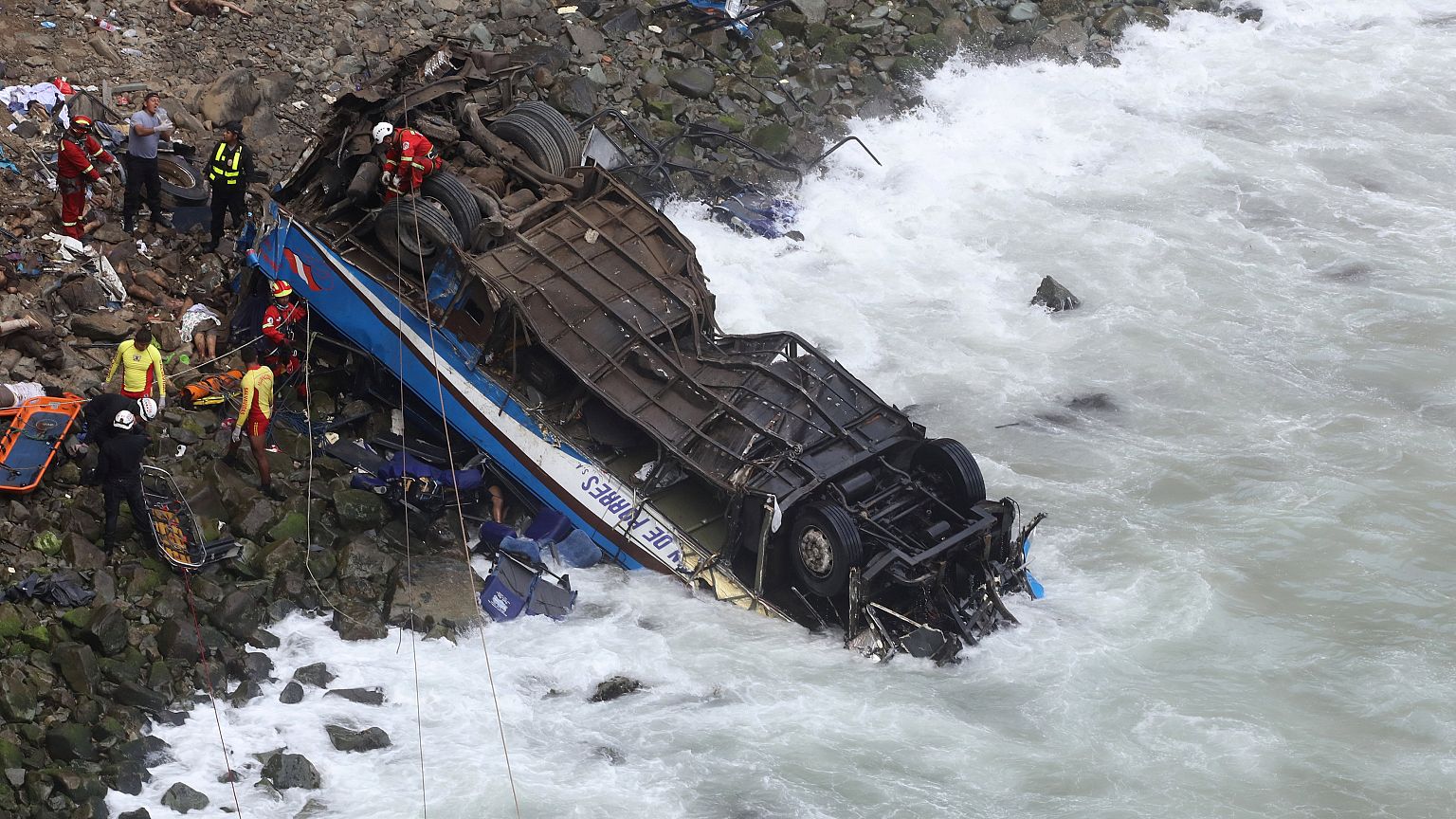 Rescue workers and police work at the scene after a bus crashed with a truc