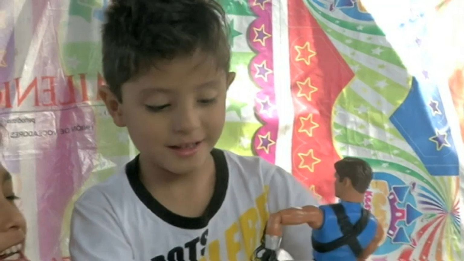 Niño juega con un juguete donado en una tienda de campaña