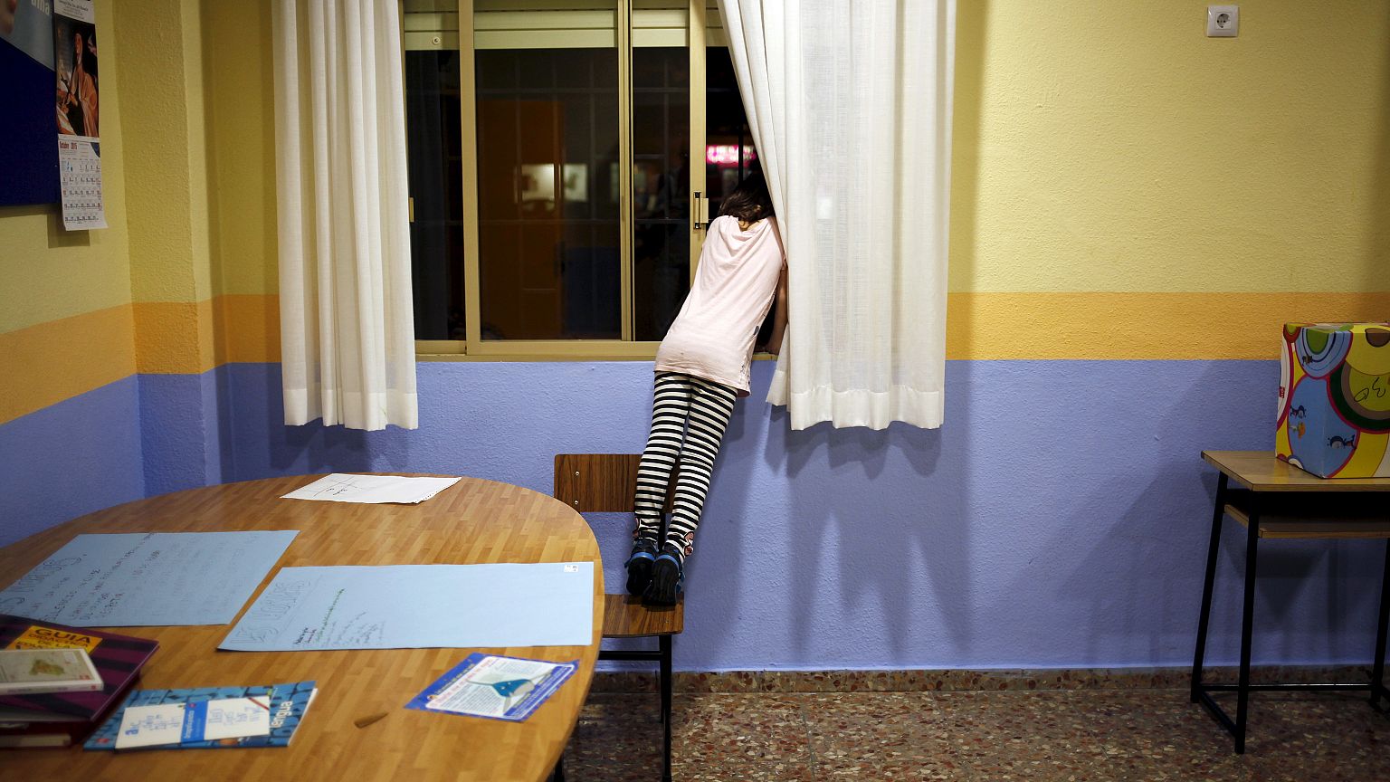 A girl looks at out at a street through a window while attending a program