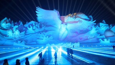 Des visiteurs admirent une gigantesque sculpture de glace à Harbin (Chine)