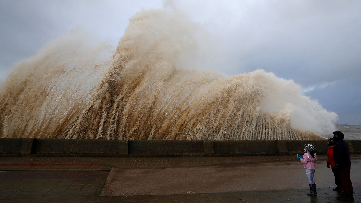 Walkers watch the waves breaking in New Brighton in Britain.