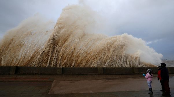 Walkers watch the waves breaking in New Brighton in Britain. Walkers watch the waves breaking in New Brighton in Britain.
