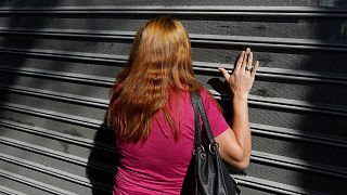 A woman bangs on the gates of a supermarket in Caracas, Jan 6