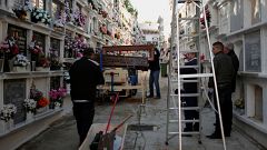 Unemployed Andres Mateo, 40, opens the cover of a coffin as he exhumes