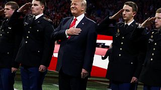 Trump stands with ROTC students to participate in the national anthem