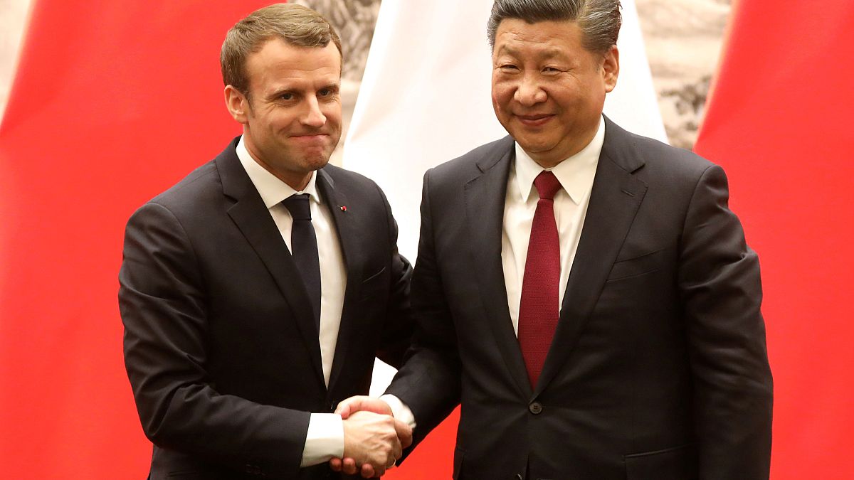 French President Emmanuel Macron (L) and Chinese President Xi Jinping shake