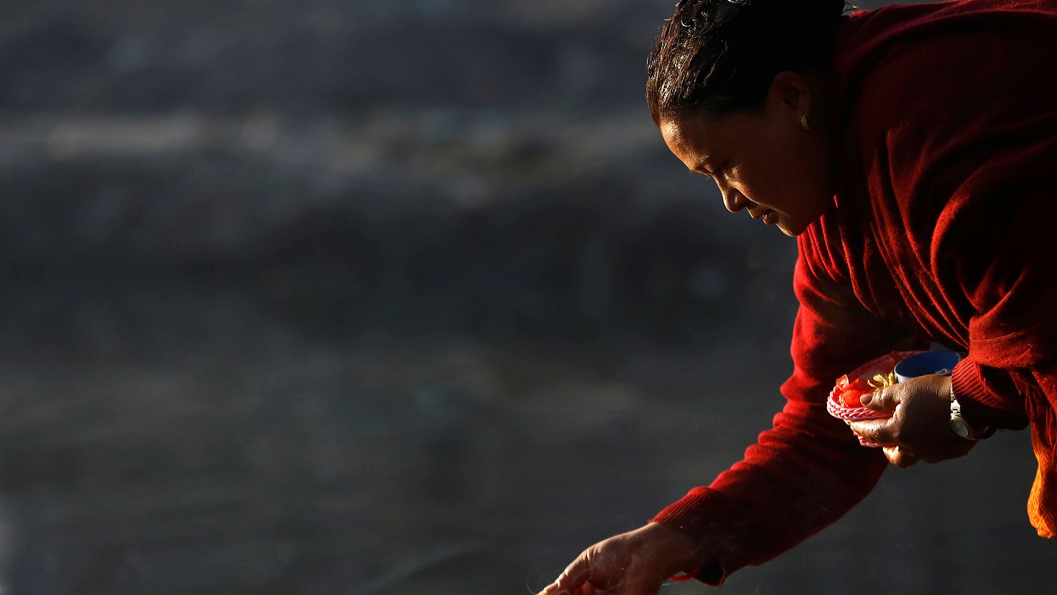 A devotee offers prayer along the bank of Hanumante River