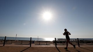 A woman exercises on a hot day in Barceloneta beach in Barcelona, Spain.