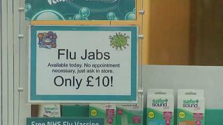 A sign in a shop window advertises the Flu vaccine