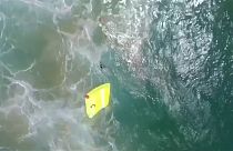 Lifeguard drone dropping float into water close to two swimmers in trouble