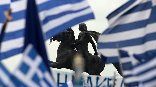 A statue of Alexander the Great is seen through waving Greek national flags A statue of Alexander the Great is seen through waving Greek national flags