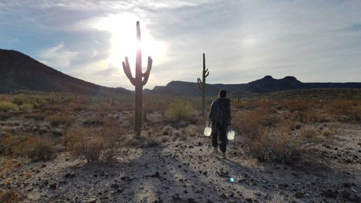 أحد المتطوعين يحمل الماء ليتركه للمهاجرين أثناء عبورهم الصحراء