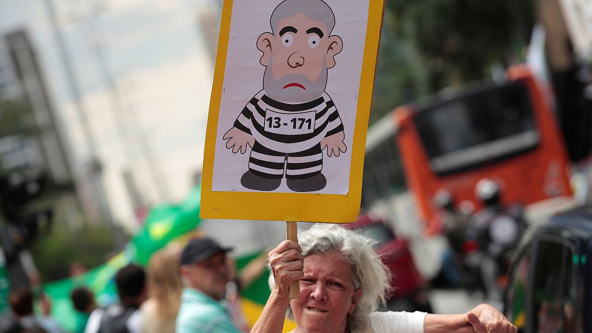Manifestante llevando una pancarte de Lula vestido de prisionero