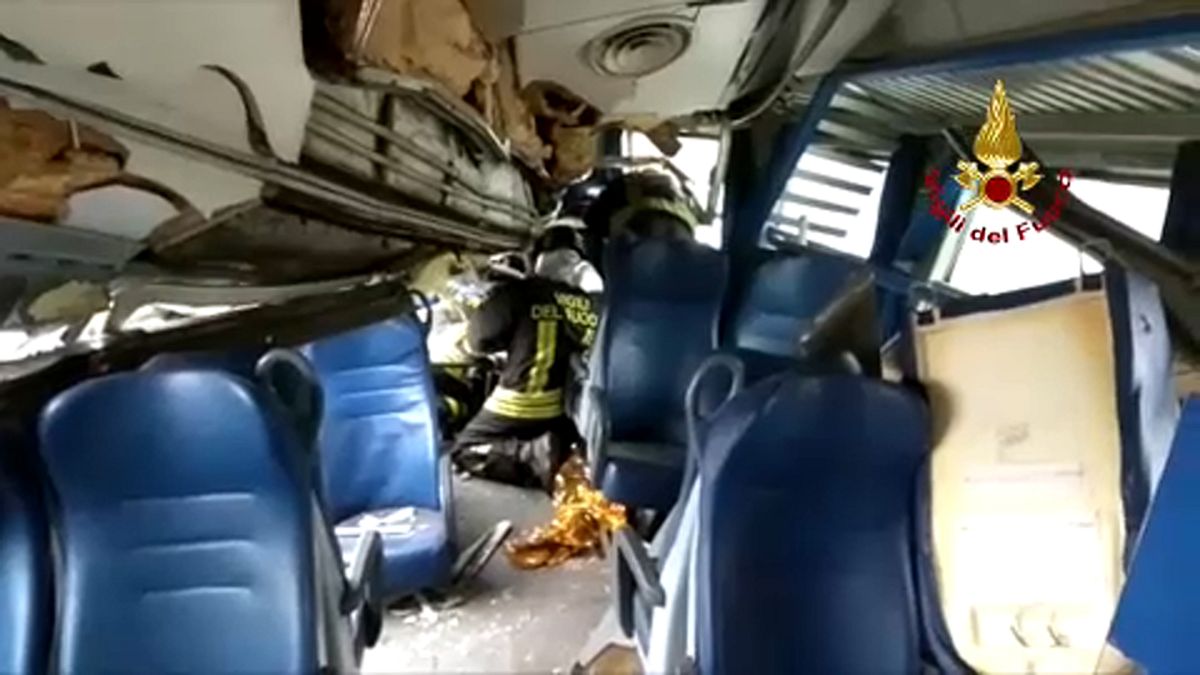 Tűzoltók dolgoznak az egyik összeroncsolódott vasúti kocsiban