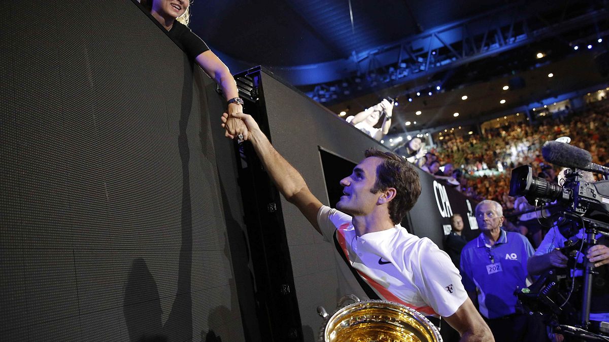 Roger Federer con su trofeo estrecha la mano de su mujer Mirka 