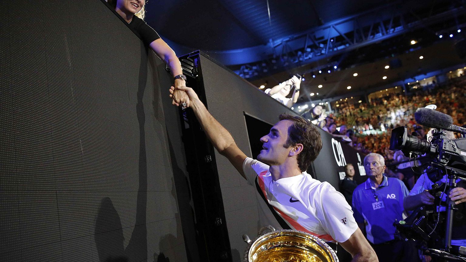 Roger Federer con su trofeo estrecha la mano de su mujer Mirka 