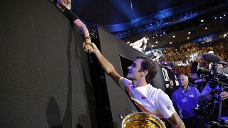 Roger Federer con su trofeo estrecha la mano de su mujer Mirka