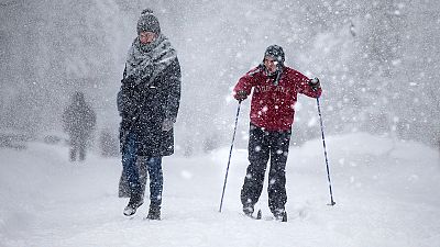Síléceken és gyalogosan közlekedők a sűrű hóesésben egy moszkvai parkban