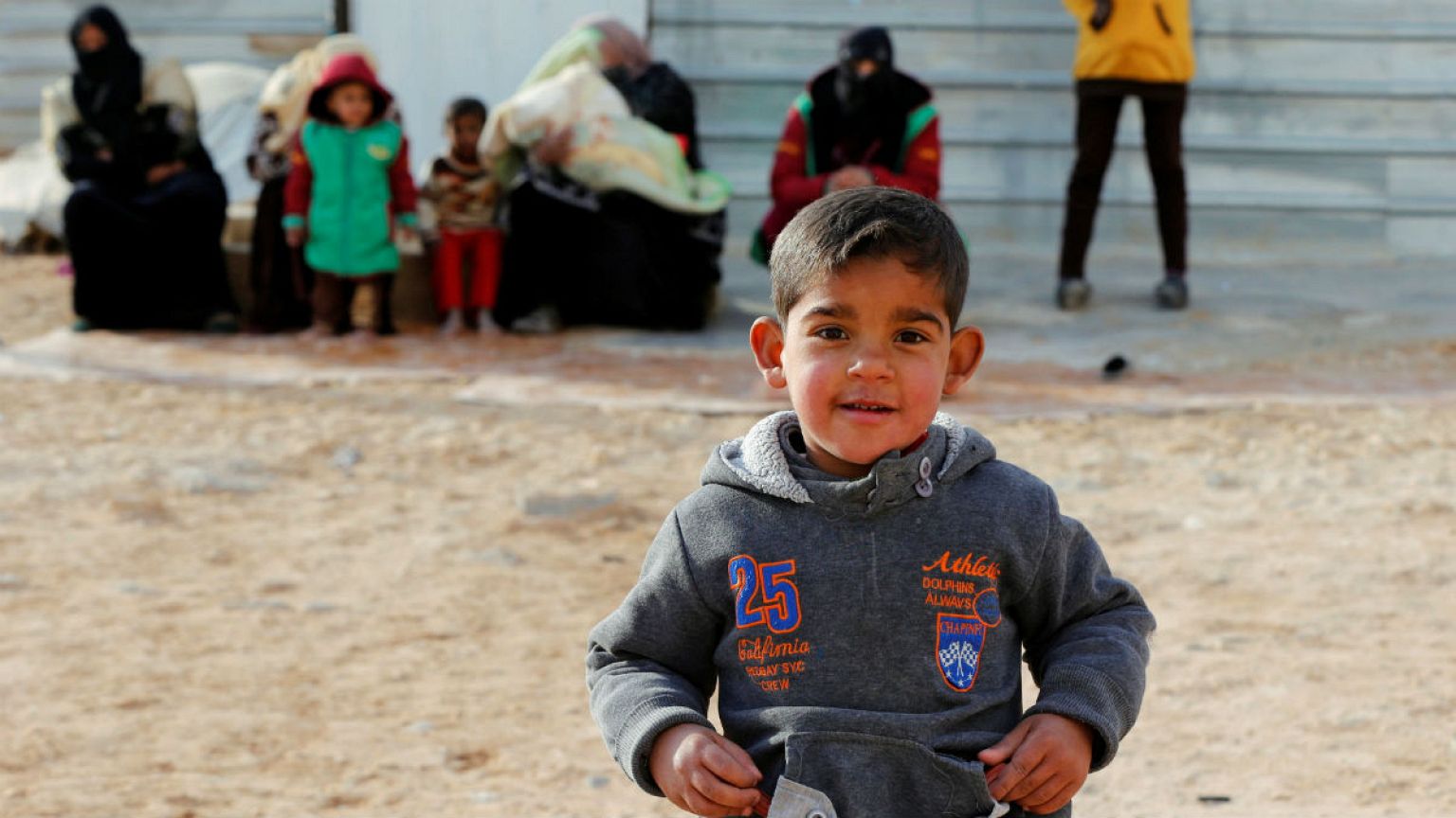 Syrian refugees sit as they wait for the arrival of actor Angelina Jolie