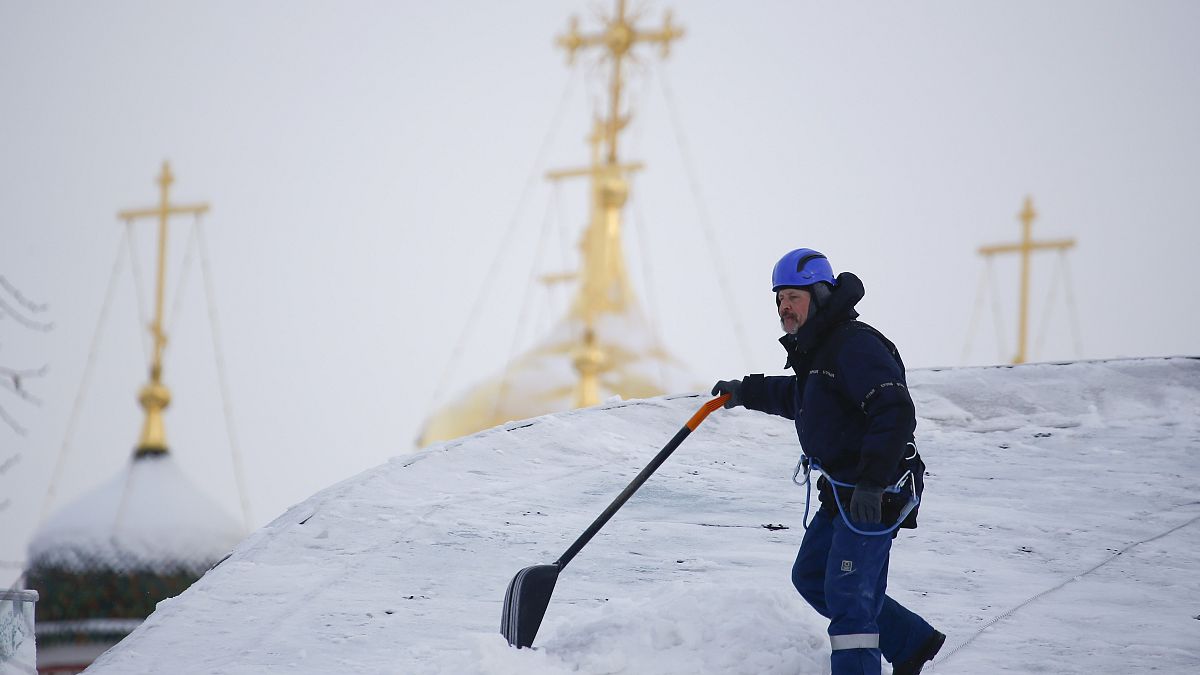 A worker removes snow from the roof of a building in Moscow