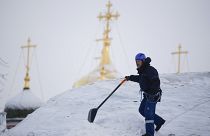 A worker removes snow from the roof of a building in Moscow