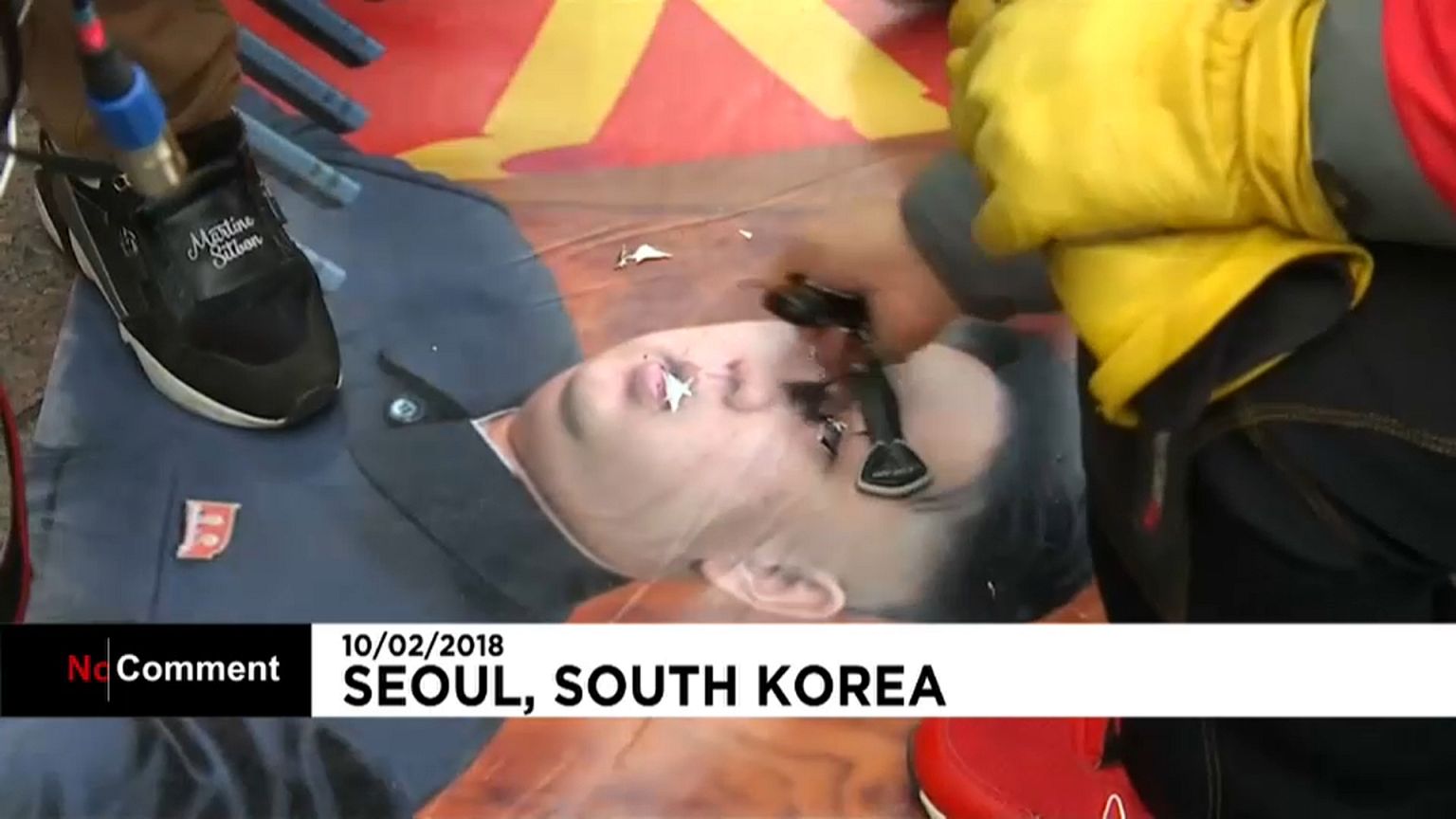 Ein Demonstrant ritzt mit einem Schlüssel in ein Bild Kim Yong Uns.