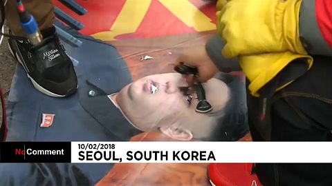 Ein Demonstrant ritzt mit einem Schlüssel in ein Bild Kim Yong Uns.
