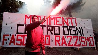 A banner reads "Movements against fascism and racism" in Macerata, Italy