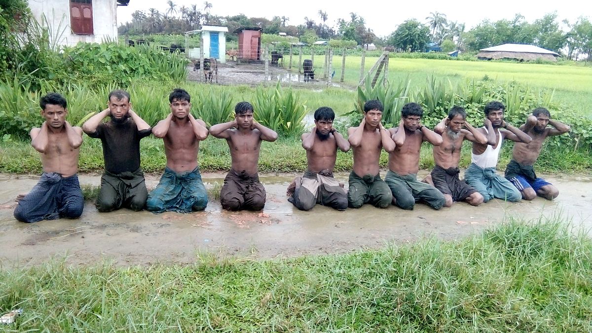Ten Rohingya Muslim men with their hands bound kneel in Inn Din village