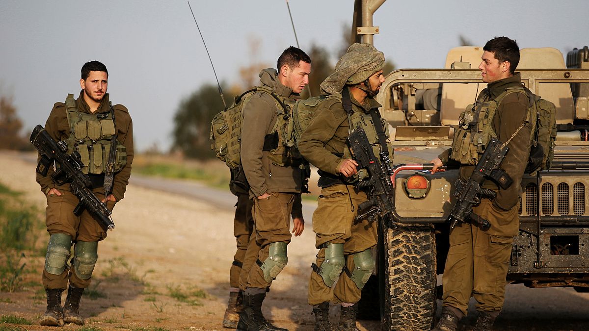جنود إسرائيليون يقفون إلى جانب آلية عسكرية بالقرب من الحدود مع قطاع غزة