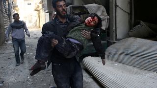شاب يحاول إسعاف طفل أصيب في القصف على الغوطة الشرقية بدمشق