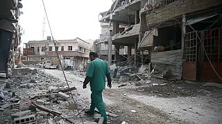 A medic walks through the rubble of a bombed clinic