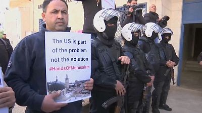 شخص يرفع لافتة للاحتجاج على زيارة وفد أمريكي للضفة الغربية