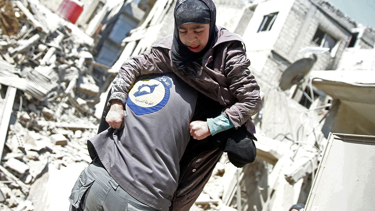 عنصر من الدفاع المدني "القبعات البيضاء" يحمل امرأة مصابة بالغوطة الشرقية