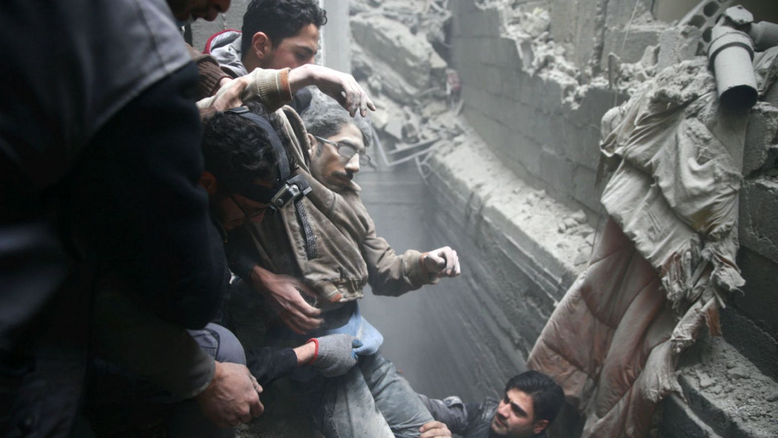 Civil defence help a man from a shelter in the besieged town of Douma