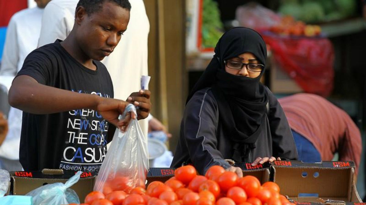 مرأة تشتري بندورة (طماطم) في سوق بجدة