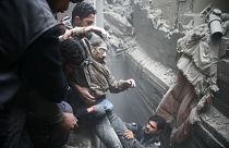Civil defence help a man from a shelter in the besieged town of Douma