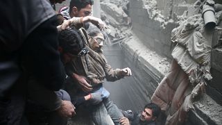 Civil defence help a man from a shelter in the besieged town of Douma