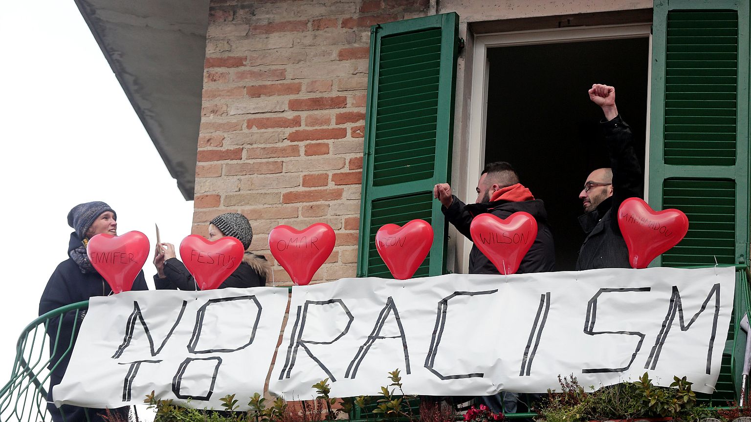 Demonstrators stand on a balcony during an anti-racism rally in Macerata.