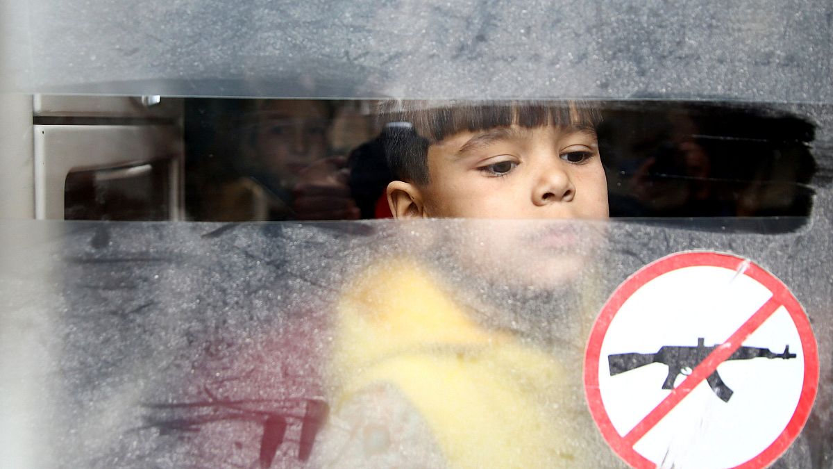 A boy looks through a bus window during evacuation from Douma, Syria