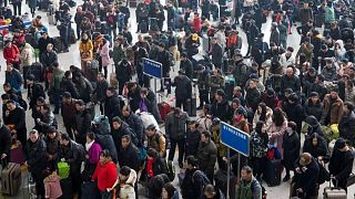مسافرون ينتظرون في محطة قطارات في الصين