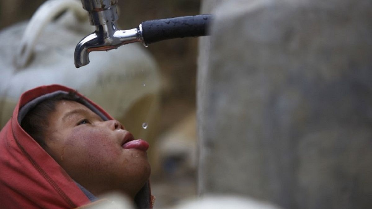طفل يشرب قطرات من ماء ينساب من صنبور في نيبال