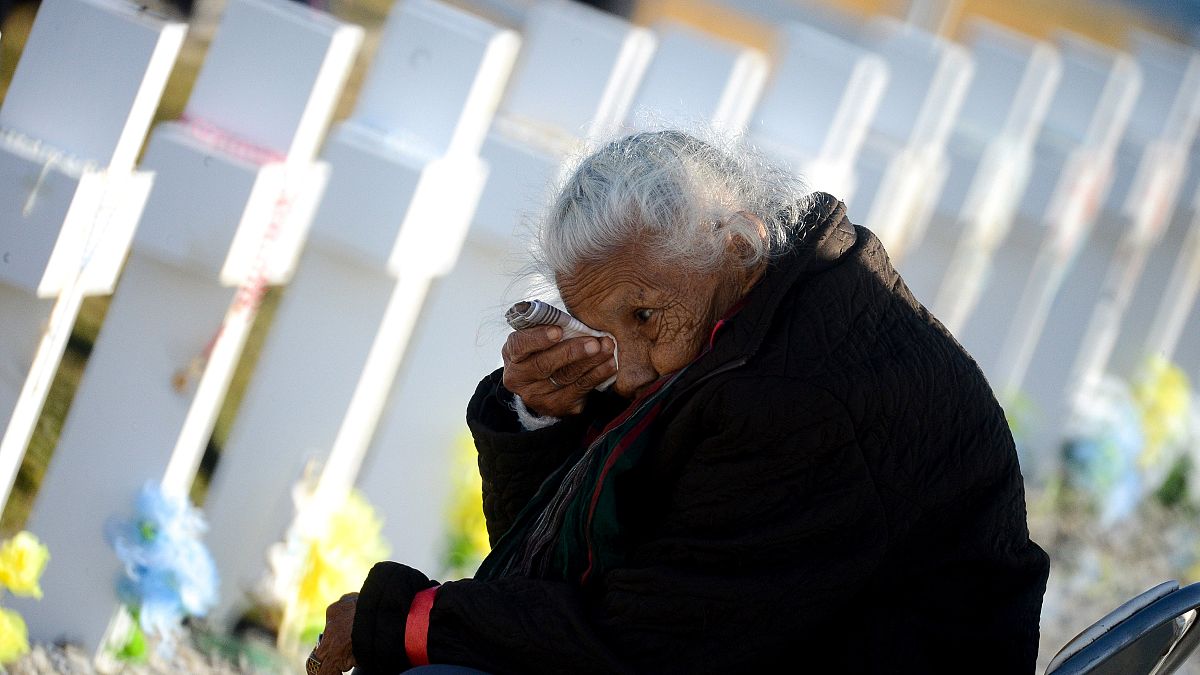 Una anciana llora junto a una de las tumbas